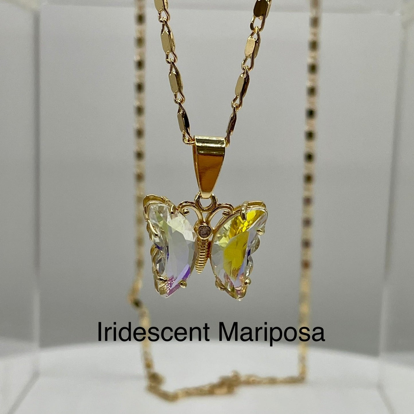 Iridescent butterfly pendant on gold necklace displayed on an acrylic base. Butterfly pendant. iridescent butterfly pendant. Mariposa pendant. Gold plated pendants.