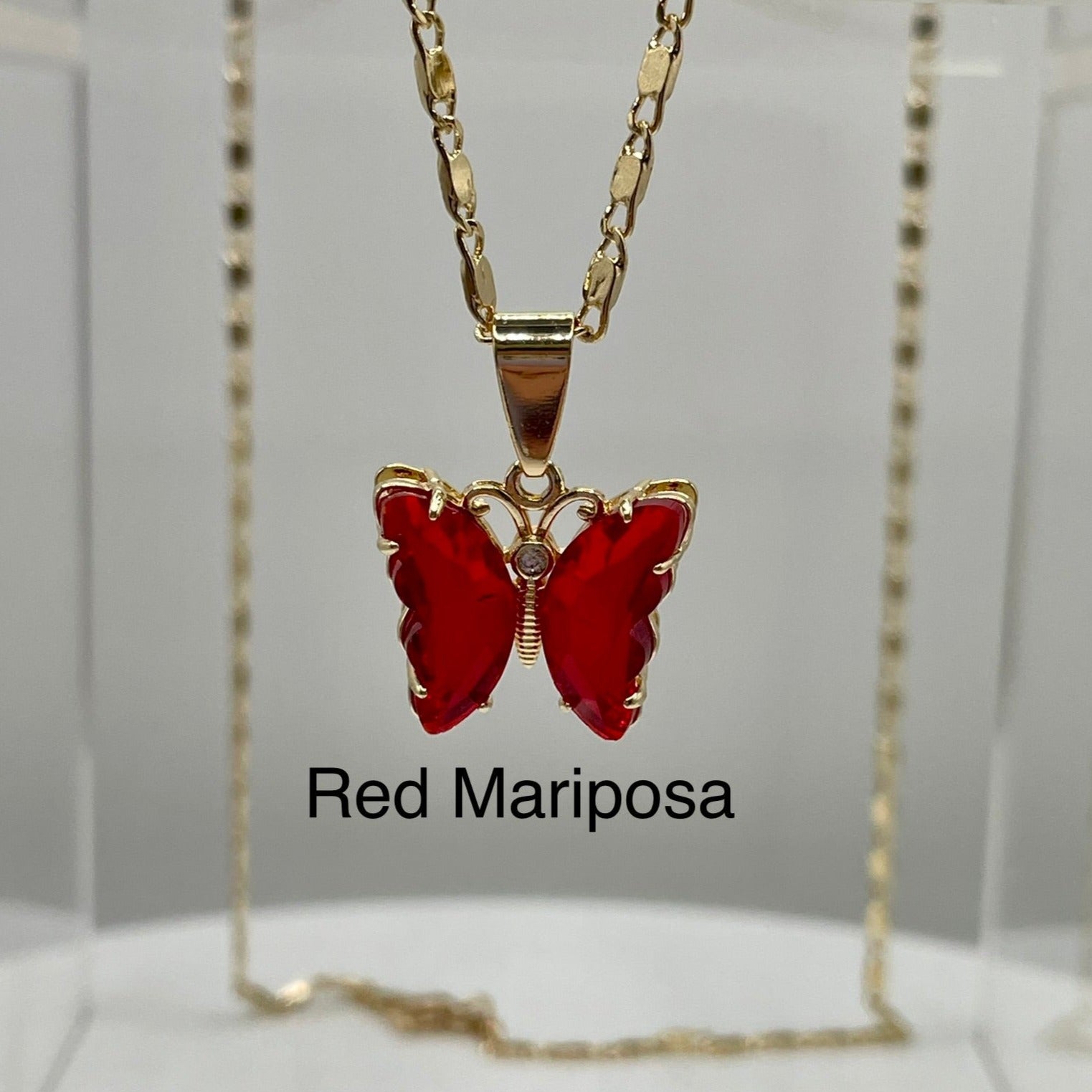 Red butterfly pendant on gold necklace displayed on an acrylic base. Butterfly pendant. iridescent butterfly pendant. Mariposa pendant. Gold plated pendants.