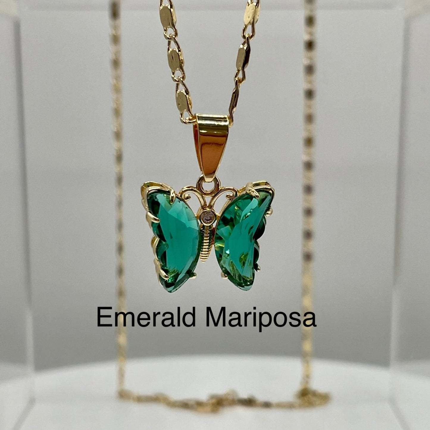 Green butterfly pendant on gold necklace displayed on an acrylic base. Butterfly pendant. iridescent butterfly pendant. Mariposa pendant. Gold plated pendants.