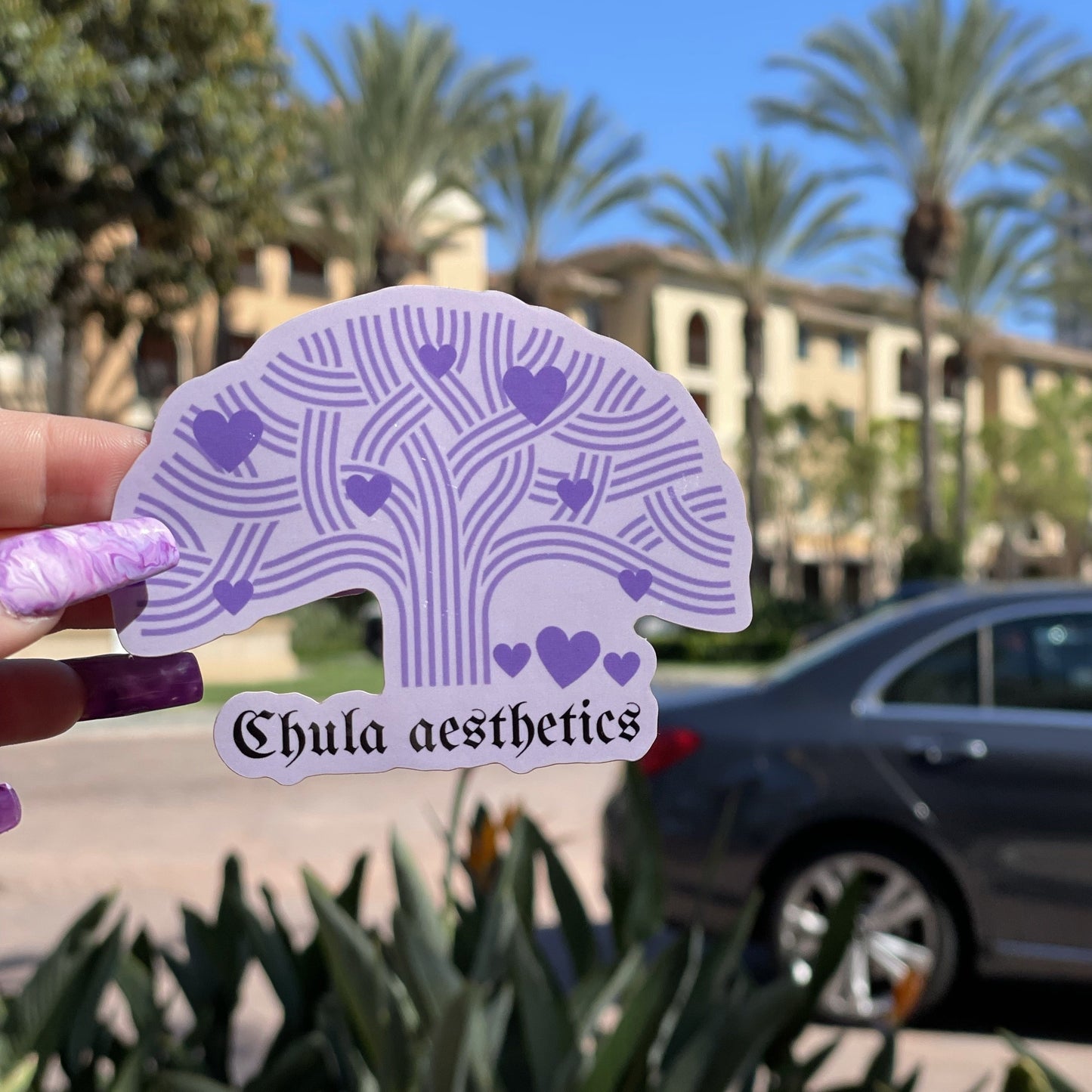 Purple Oakland tree with purple hearts and Chula aesthetics name/logo being held by a hand.